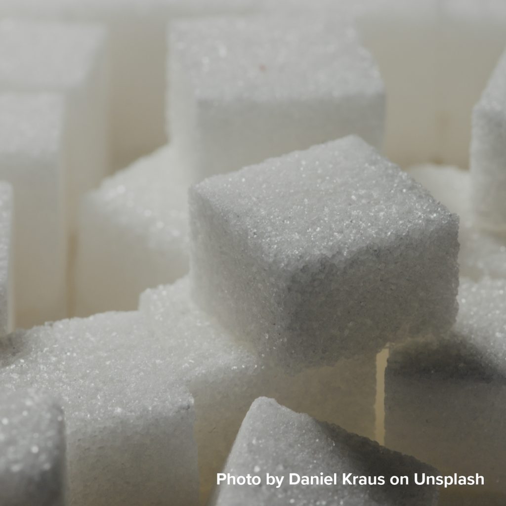 Close-up of a group of white sugar cubes stacked together, highlighting their granular texture and geometric shapes, conveying simplicity and purity.