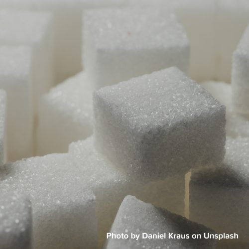 Close-up of a group of white sugar cubes stacked together, highlighting their granular texture and geometric shapes, conveying simplicity and purity.